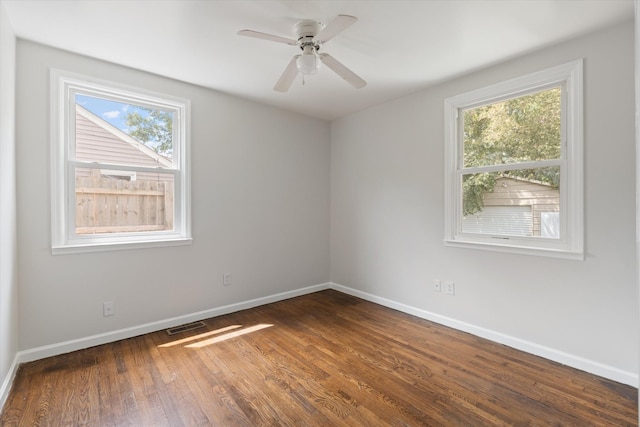 unfurnished room with ceiling fan, a healthy amount of sunlight, and dark wood-type flooring