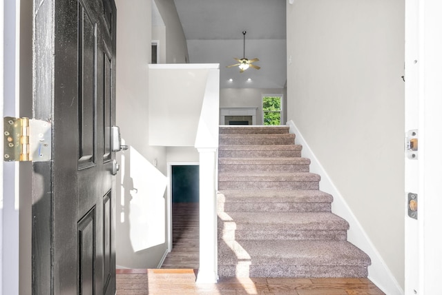 foyer with hardwood / wood-style floors, ceiling fan, and a high ceiling