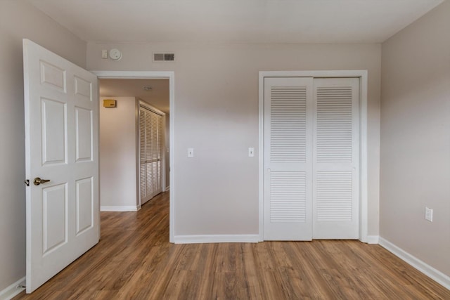 unfurnished bedroom with a closet and dark hardwood / wood-style floors