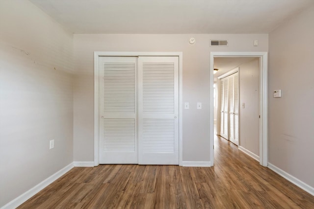 unfurnished bedroom featuring a closet and dark wood-type flooring