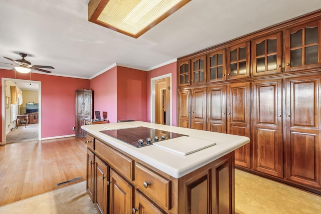 kitchen with ceiling fan, light hardwood / wood-style flooring, crown molding, black electric cooktop, and a kitchen island