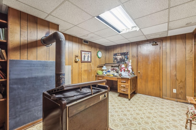 home office with a drop ceiling and wood walls