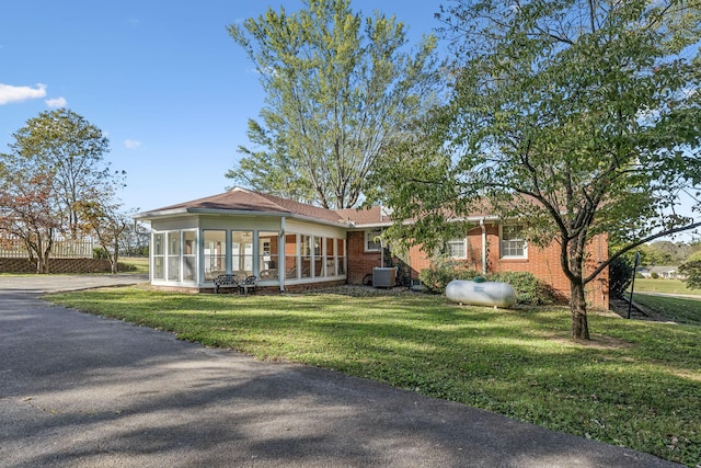 view of front of property with a sunroom, cooling unit, and a front lawn