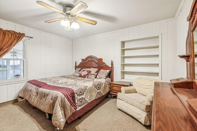 carpeted bedroom featuring ceiling fan, ornamental molding, and wooden walls