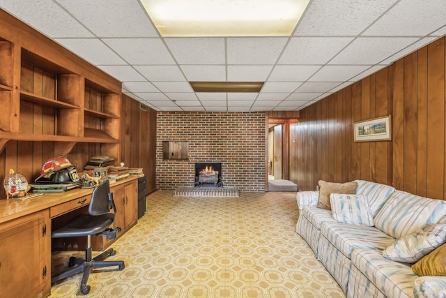 office featuring a drop ceiling, wood walls, a wood stove, and brick wall