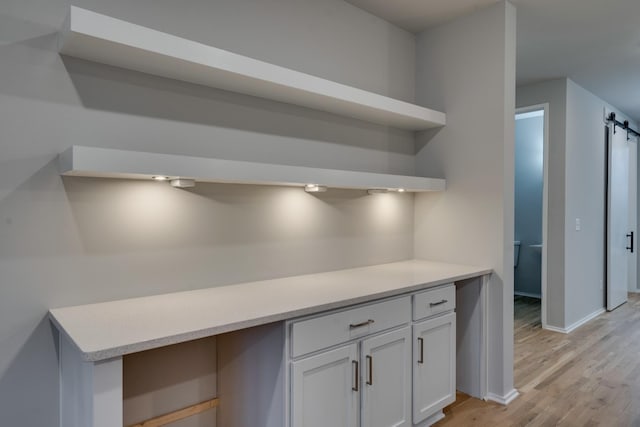 kitchen with white cabinets, light wood-type flooring, and a barn door