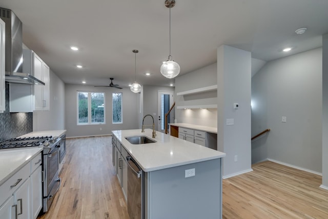 kitchen featuring white cabinets, hanging light fixtures, sink, an island with sink, and appliances with stainless steel finishes