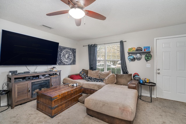 living room featuring ceiling fan, light colored carpet, and a textured ceiling