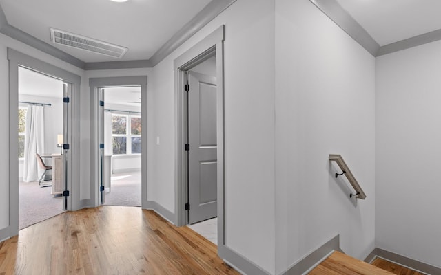 corridor featuring light wood-type flooring and crown molding