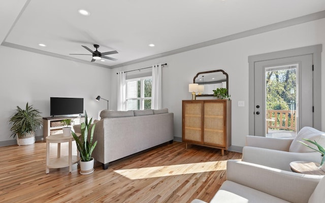 living room with ceiling fan, light hardwood / wood-style flooring, a healthy amount of sunlight, and ornamental molding