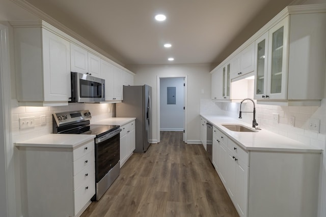 kitchen with white cabinets, sink, stainless steel appliances, and hardwood / wood-style flooring