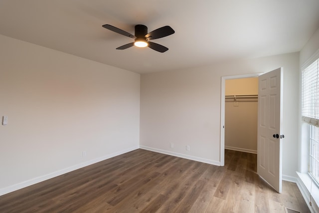 unfurnished bedroom featuring a closet, hardwood / wood-style flooring, a spacious closet, and ceiling fan