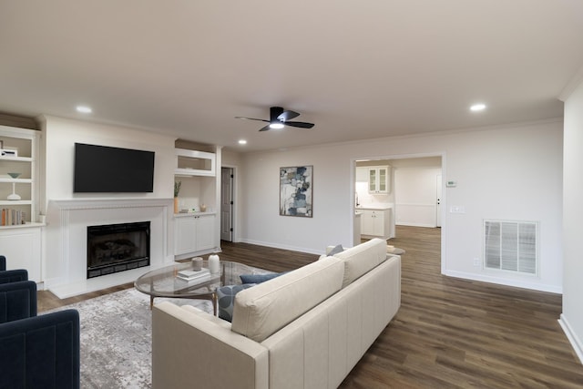 living room with crown molding, ceiling fan, and dark hardwood / wood-style floors