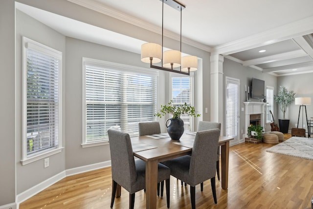 dining space featuring beam ceiling, light hardwood / wood-style flooring, and a healthy amount of sunlight