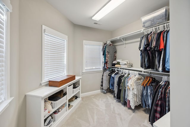 walk in closet with light carpet