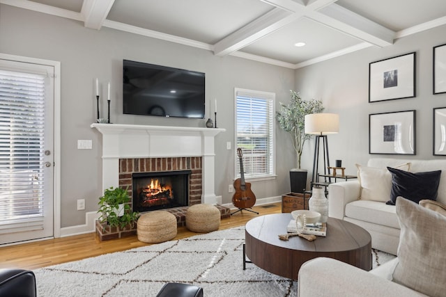 living room with hardwood / wood-style floors, crown molding, beamed ceiling, and a brick fireplace