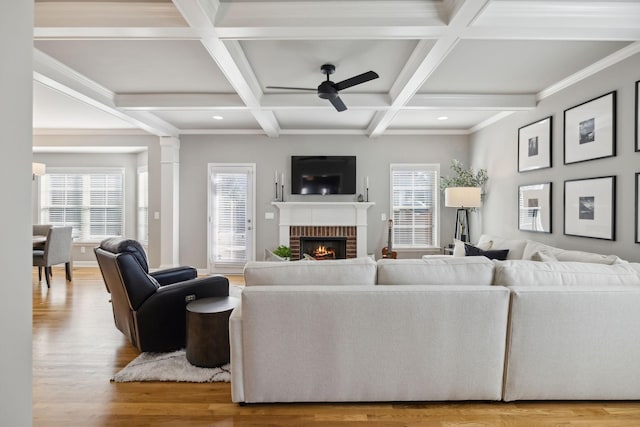 living room with ceiling fan, coffered ceiling, a brick fireplace, beamed ceiling, and hardwood / wood-style flooring