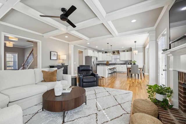 living room featuring ceiling fan, plenty of natural light, coffered ceiling, and ornamental molding