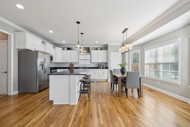 kitchen featuring backsplash, stainless steel appliances, a kitchen island, light hardwood / wood-style flooring, and white cabinetry