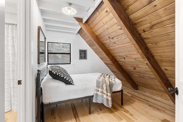 bedroom with vaulted ceiling with beams, light wood-type flooring, and wooden ceiling