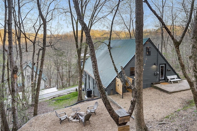 rear view of property featuring central air condition unit and an outdoor fire pit