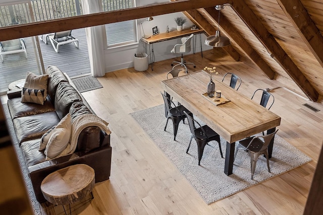 dining space featuring lofted ceiling with beams and light hardwood / wood-style floors