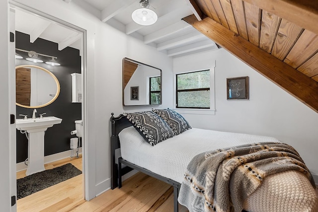 bedroom with beamed ceiling, light wood-type flooring, and sink