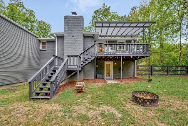 back of house featuring an outdoor fire pit, a lawn, and a deck