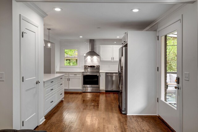 kitchen featuring hanging light fixtures, appliances with stainless steel finishes, plenty of natural light, and wall chimney range hood