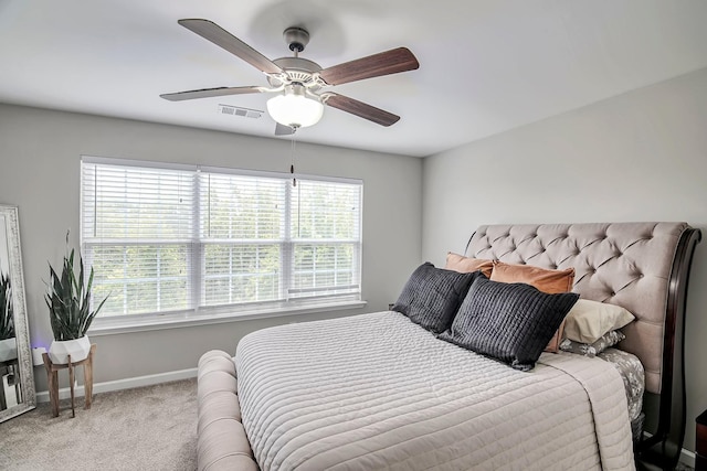 bedroom with multiple windows, ceiling fan, and light carpet