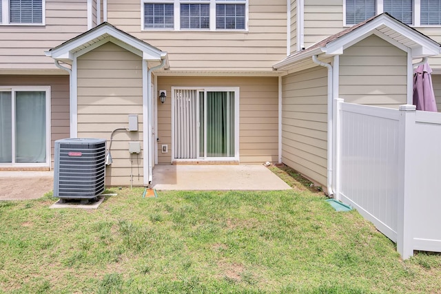 entrance to property with central air condition unit, a patio area, and a lawn