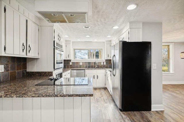 kitchen featuring kitchen peninsula, a textured ceiling, stainless steel appliances, and light hardwood / wood-style flooring