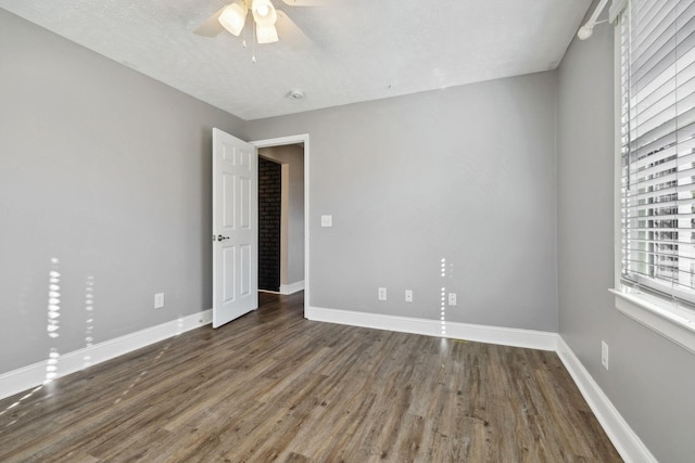 unfurnished room featuring ceiling fan, dark wood-type flooring, and a textured ceiling