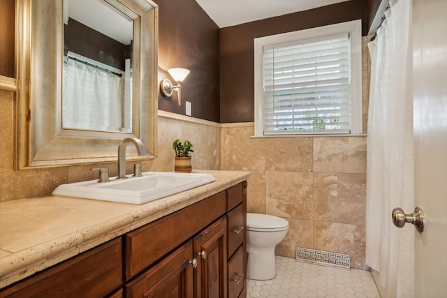 bathroom with tile patterned floors, vanity, toilet, and tile walls