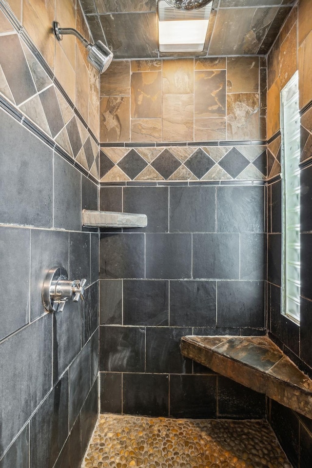 bathroom with a tile shower and tile walls