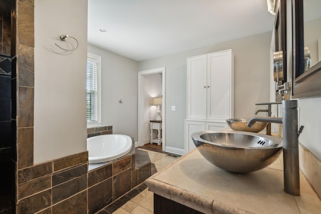 bathroom with tile patterned flooring, vanity, and tiled bath