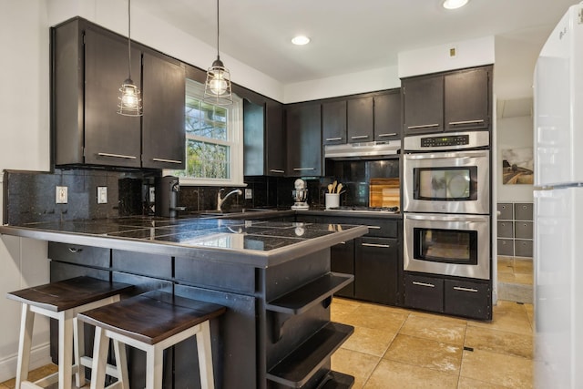 kitchen featuring dark brown cabinetry, stainless steel appliances, decorative light fixtures, a kitchen bar, and decorative backsplash