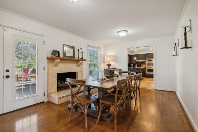 dining room with crown molding, a fireplace, and hardwood / wood-style flooring