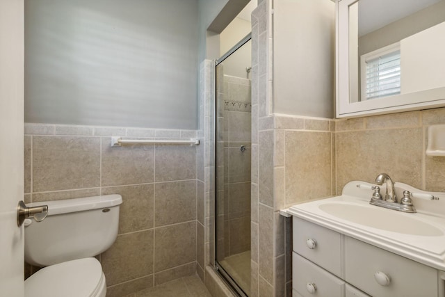 bathroom with vanity, toilet, a shower with door, and tile walls