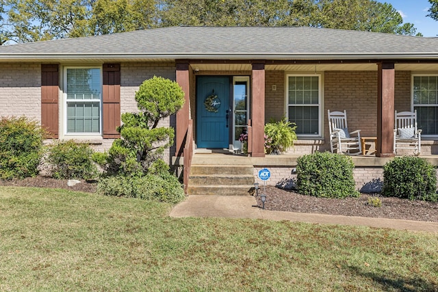 doorway to property with a porch and a yard