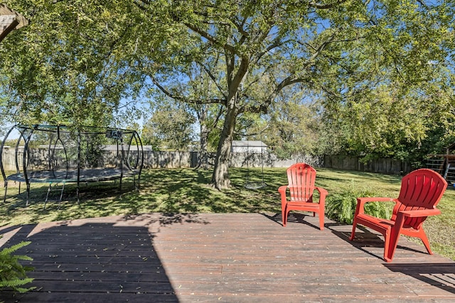 wooden terrace with a trampoline and a yard