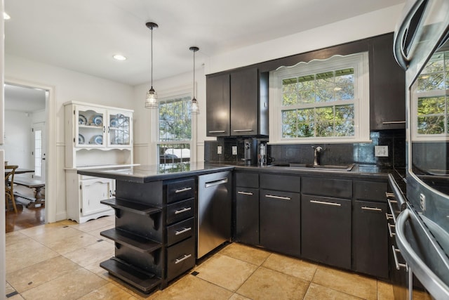 kitchen featuring kitchen peninsula, decorative backsplash, pendant lighting, and appliances with stainless steel finishes