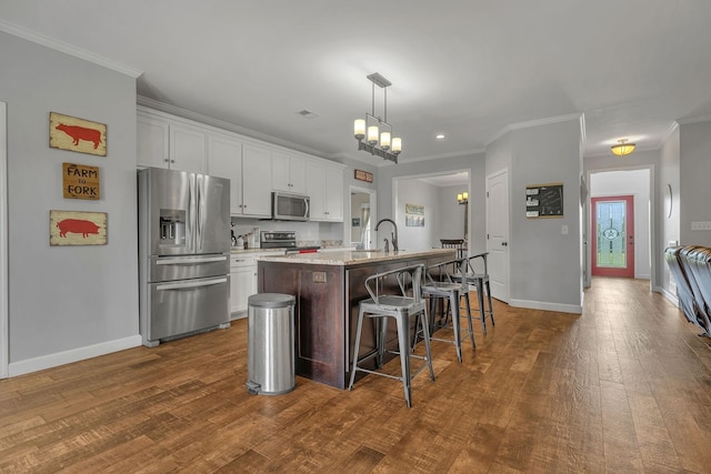 kitchen featuring white cabinets, a kitchen bar, stainless steel appliances, and an island with sink