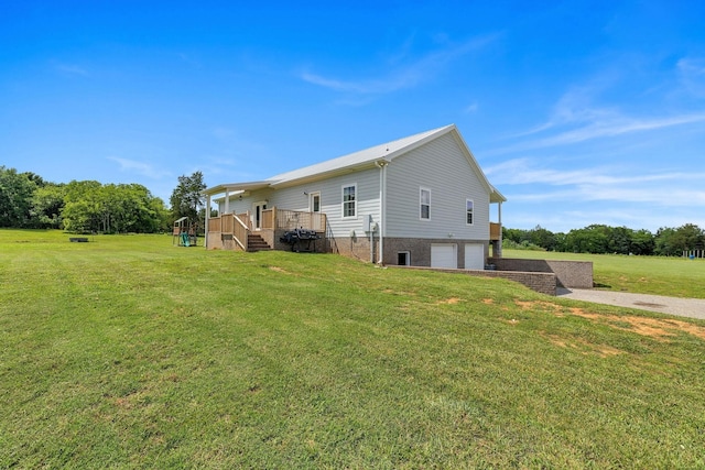 rear view of house featuring a lawn, a garage, and a deck