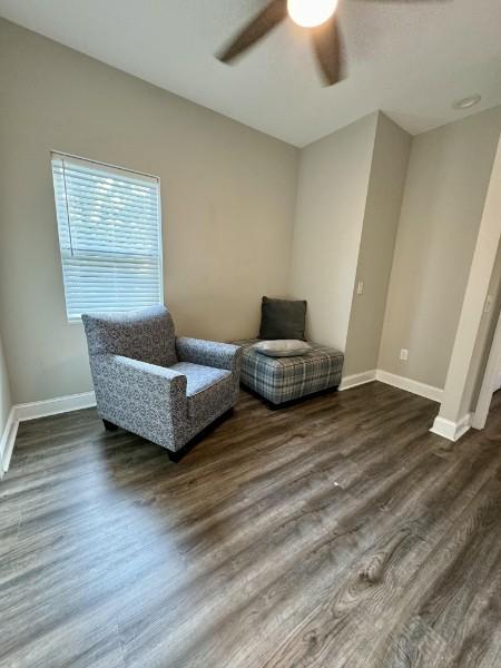 living area featuring dark hardwood / wood-style flooring and ceiling fan