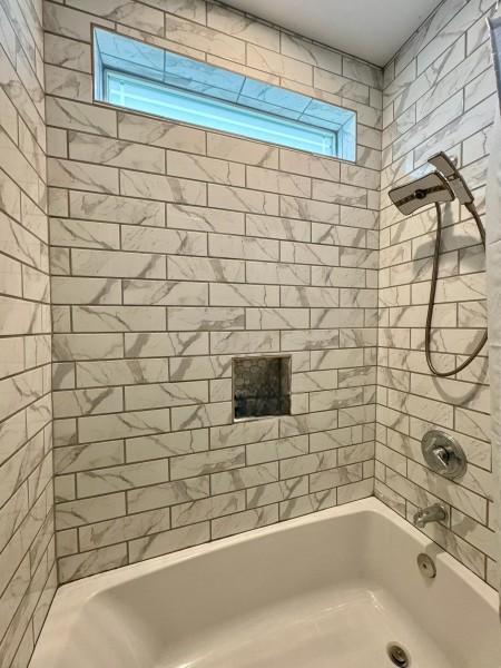 bathroom with plenty of natural light and tiled shower / bath