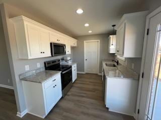 kitchen with stainless steel appliances, dark wood-type flooring, sink, decorative light fixtures, and white cabinetry