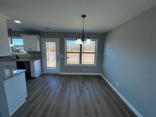 kitchen featuring sink, hanging light fixtures, dark wood-type flooring, an inviting chandelier, and white cabinets