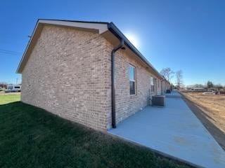 view of side of property featuring a patio area, central air condition unit, and a yard