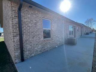 view of side of property with a patio area and central AC unit